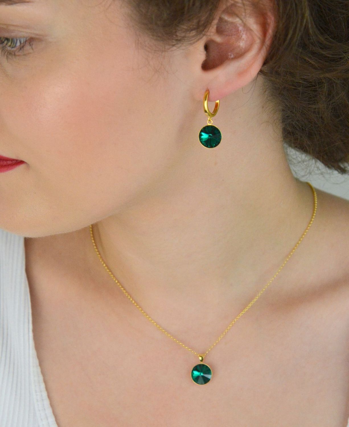 Kolczyki Spark z pozłacanego srebra 925, ozdobione kryształami w kolorze Emerald. Długość 2,7 cm, zapięcie na zatrzask. Stylowa elegancja na co dzień i wieczór.1.webp