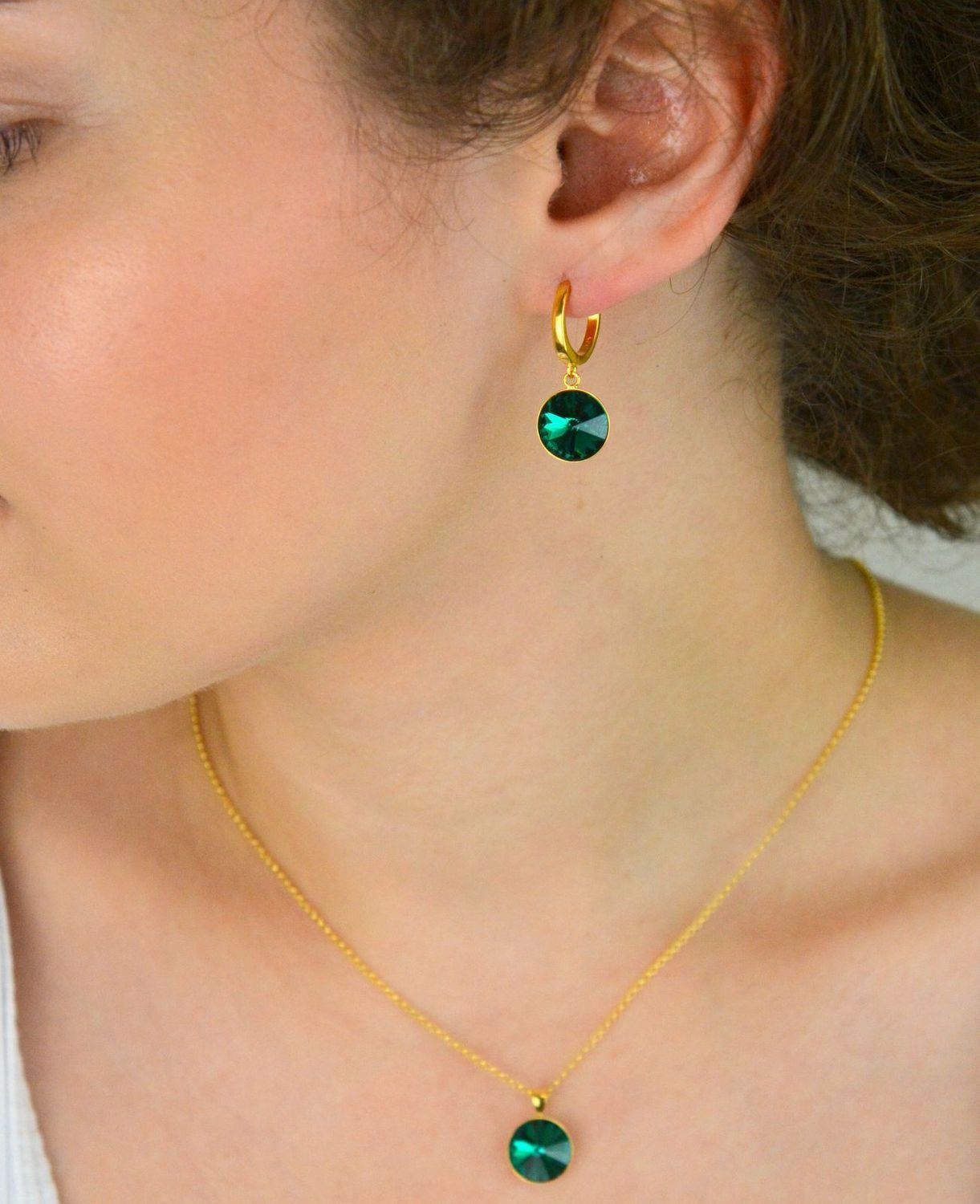 Kolczyki Spark z pozłacanego srebra 925, ozdobione kryształami w kolorze Emerald. Długość 2,7 cm, zapięcie na zatrzask. Stylowa elegancja na co dzień i wieczór.1.webp