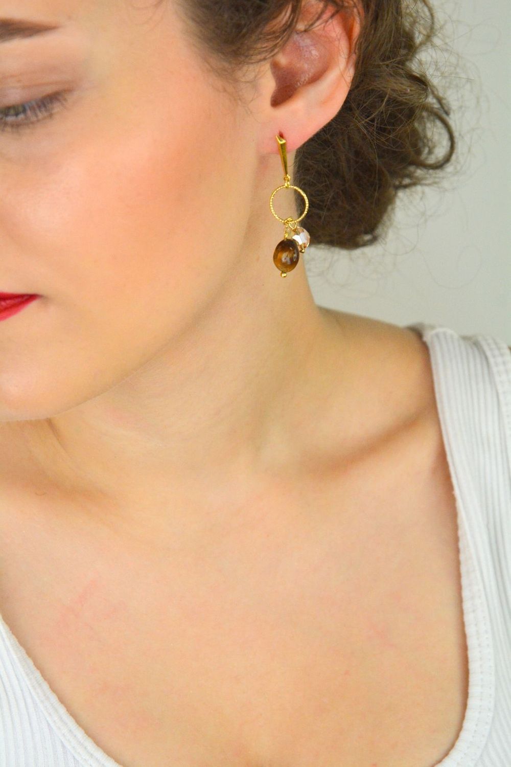 Eleganckie kolczyki Delicado ze srebra próby 925, pozłacane, z kamieniami tygrysiego oka i kryształami w odcieniu Golden Shadow. Zapięcie typu sztyft. Długość 5,5 cm.1.webp