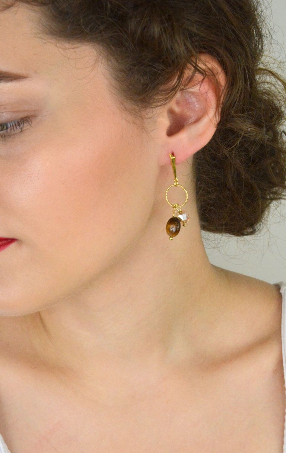 Eleganckie kolczyki Delicado ze srebra próby 925, pozłacane, z kamieniami tygrysiego oka i kryształami w odcieniu Golden Shadow. Zapięcie typu sztyft. Długość 5,5 cm.1.webp