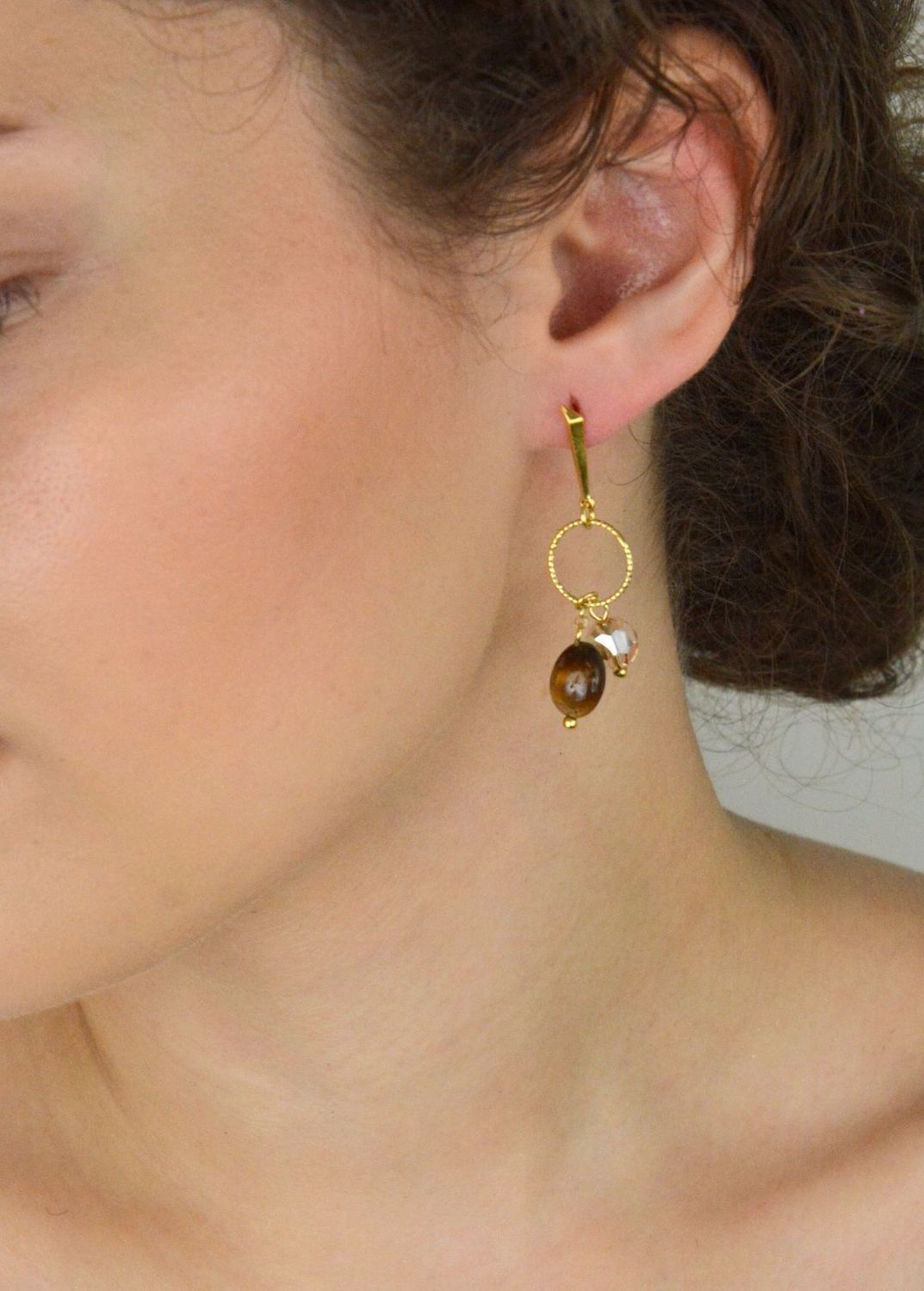 Eleganckie kolczyki Delicado ze srebra próby 925, pozłacane, z kamieniami tygrysiego oka i kryształami w odcieniu Golden Shadow. Zapięcie typu sztyft. Długość 5,5 cm.1.webp