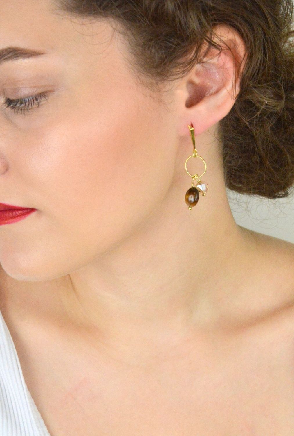 Eleganckie kolczyki Delicado ze srebra próby 925, pozłacane, z kamieniami tygrysiego oka i kryształami w odcieniu Golden Shadow. Zapięcie typu sztyft. Długość 5,5 cm.1.webp