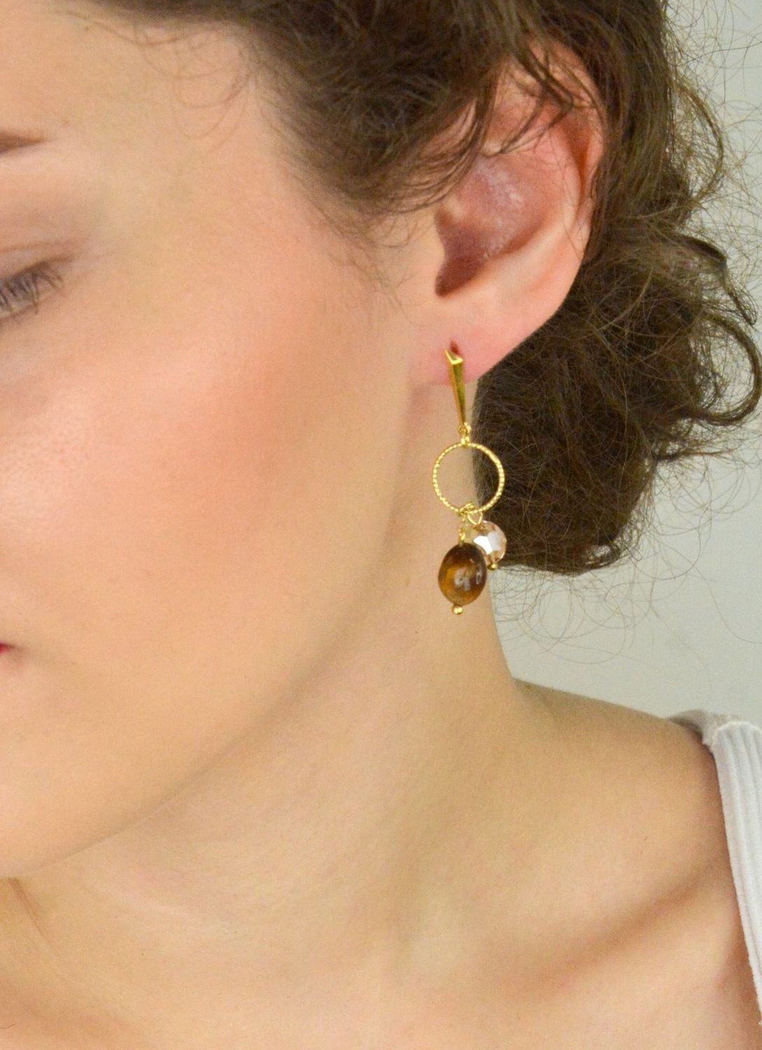 Eleganckie kolczyki Delicado ze srebra próby 925, pozłacane, z kamieniami tygrysiego oka i kryształami w odcieniu Golden Shadow. Zapięcie typu sztyft. Długość 5,5 cm.1.webp