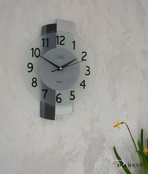 Zegar ścienny drewniany ze szkłem JVD szary NS19043.1. Nowoczesny zegar ścienny do salonu JVD NS19043.1 wyposażony jest w kwarcowy mechanizm, zasilany za pomocąka w srebrnej kolorystyce z czarnym (6).JPG