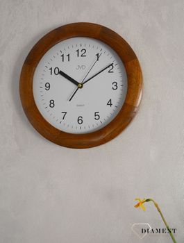 Zegar na ścianę drewniany JVD NS7017.1 okrągły. Model posiada mechanizm zegarowy z płynącym sekundnikiem. Zegar wyposażony w szkło mineralne. Zegar ścienny w okrągłej drewnianej obudowie. Tarcza zegarka w kolorze białym (3).JPG