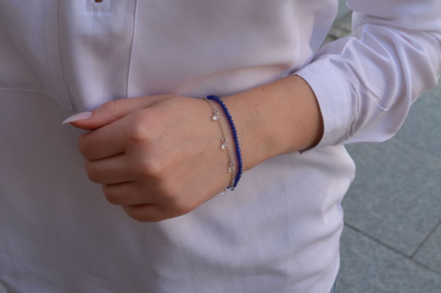 Srebrna bransoletka z niebieskimi koralikami z drugim delikatnym, ażurkowym łańcuszku na którym znajdują się białe kryształki. Zapinanie na karabińczyk..jpg