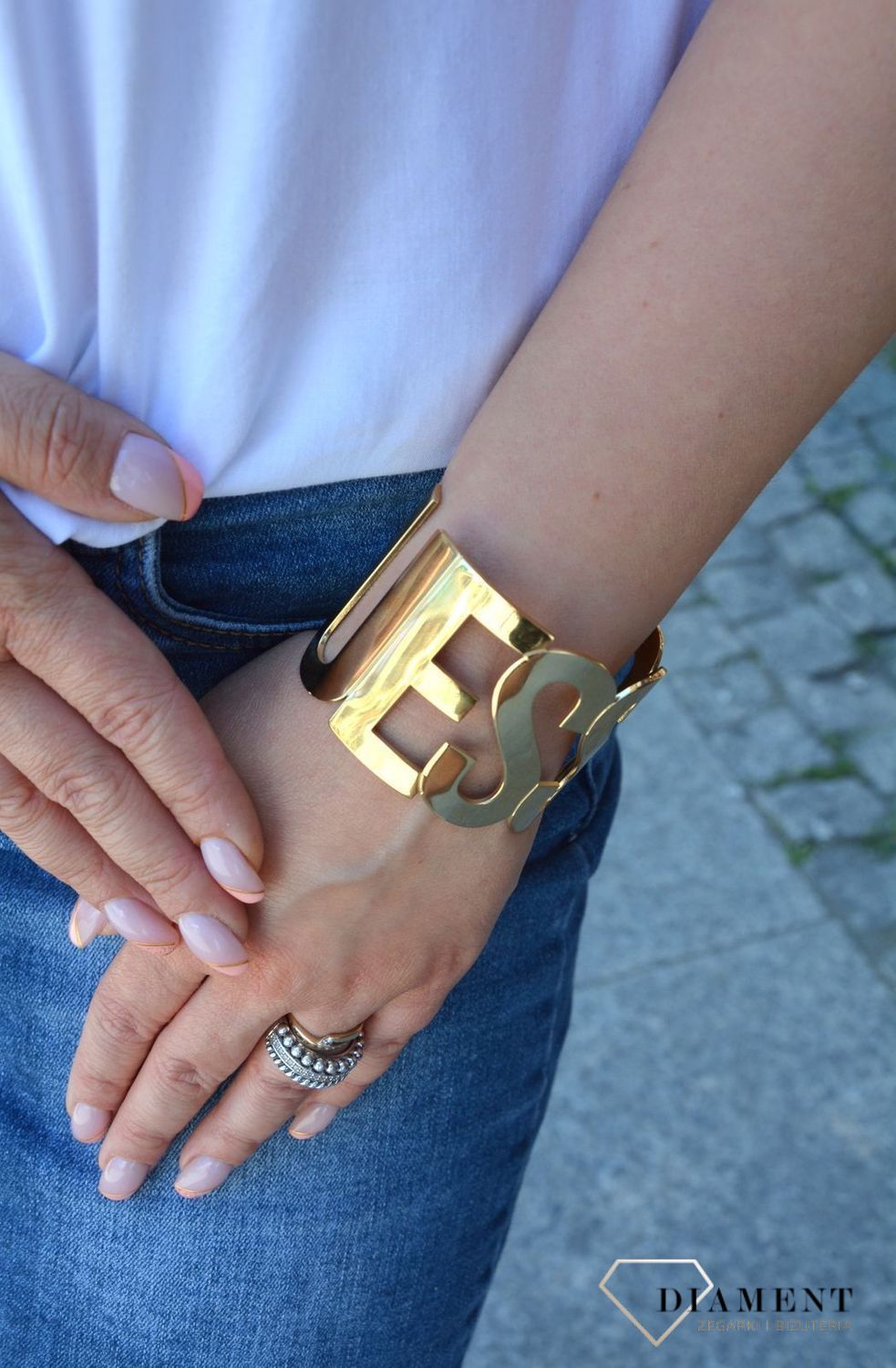 Bransoletka pozłacana sztywna napis GUESS UBB20001-S. Sztywna, stalowa bransoletka w kolorze złotym z elementem ozdobnym w formie napisu 'Guess'. Wyrazista ozdoba, która świetnie się sprawdzi jako dodatek do letnich.jpg