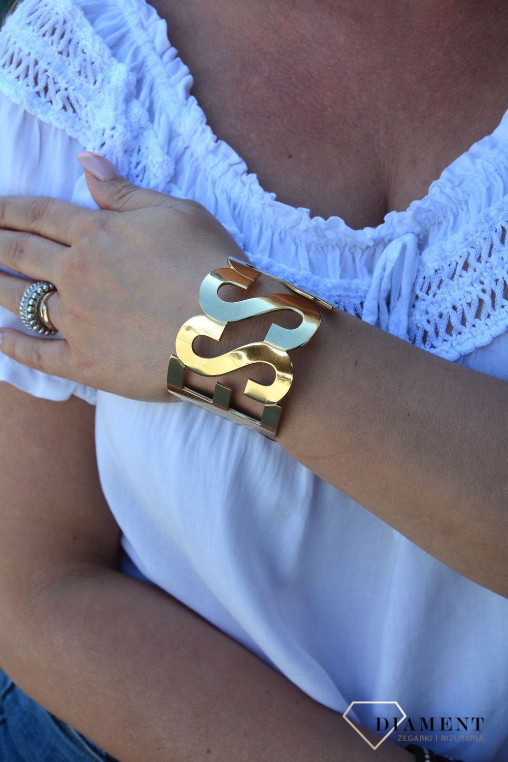 Bransoletka pozłacana sztywna napis GUESS UBB20001-S. Sztywna, stalowa bransoletka w kolorze złotym z elementem ozdobnym w formie napisu 'Guess'. Wyrazista ozdoba, która świetnie się sprawdzi jako dodatek do letnich.jpg