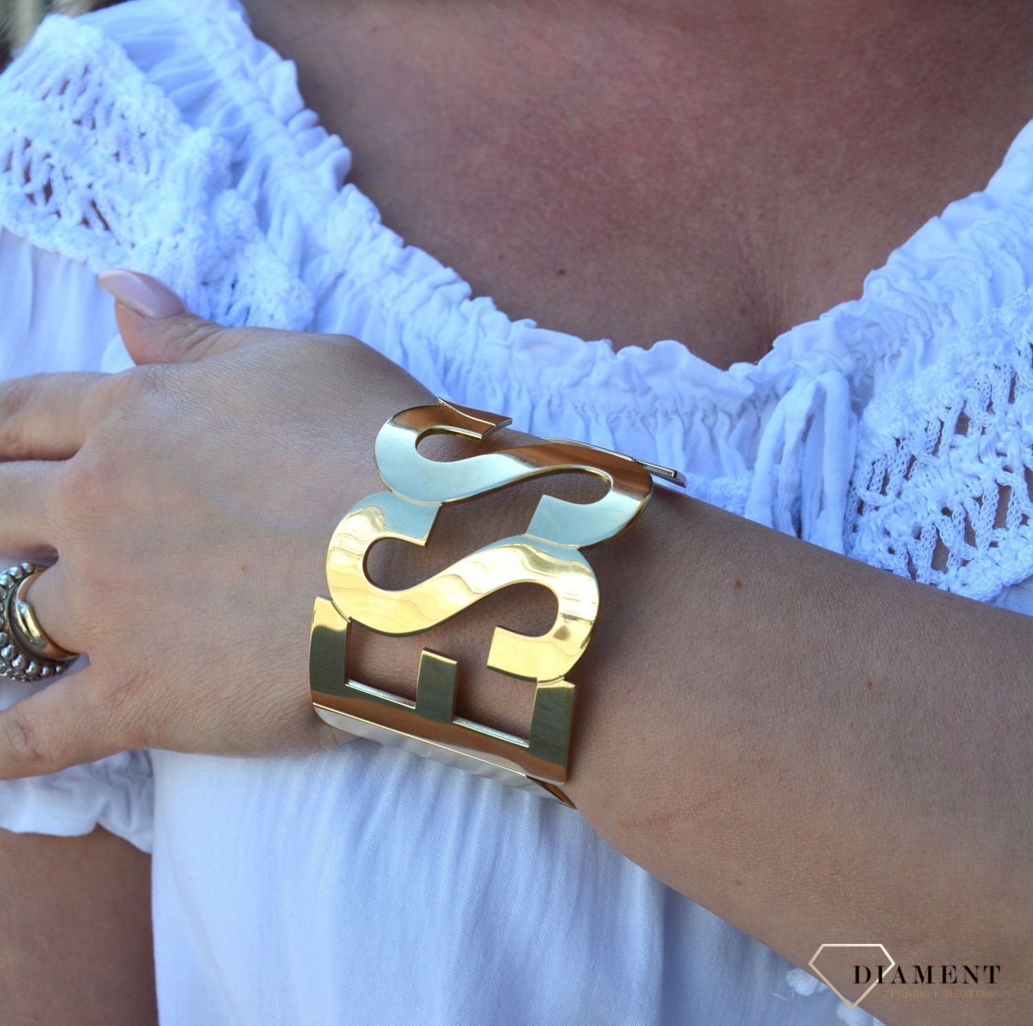 Bransoletka pozłacana sztywna napis GUESS UBB20001-S. Sztywna, stalowa bransoletka w kolorze złotym z elementem ozdobnym w formie napisu 'Guess'. Wyrazista ozdoba, która świetnie się sprawdzi jako dodatek do letnich.jpg