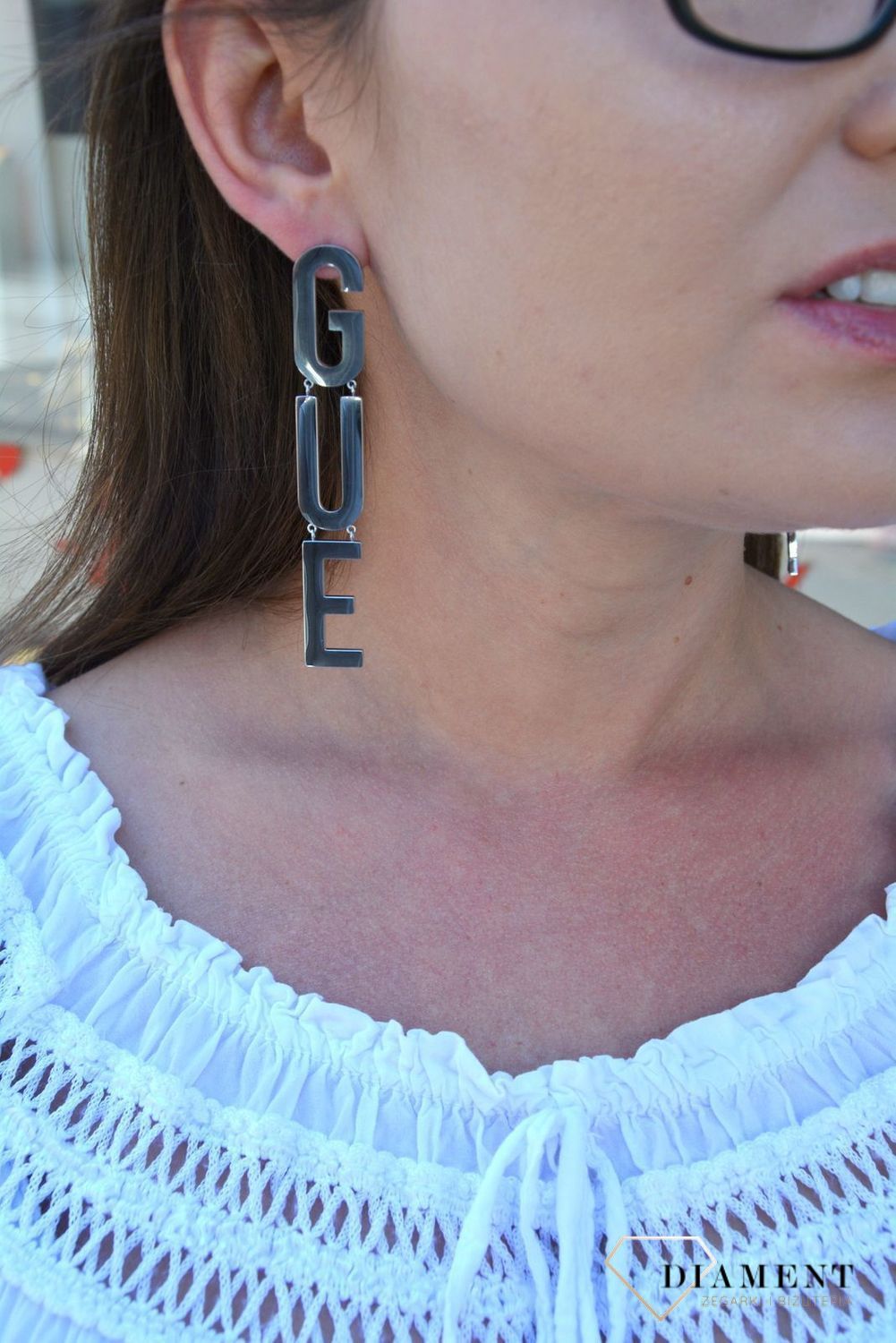 Kolczyki GUESS stalowe duży napis Guess UBE20002. Stalowe kolczyki duży napis Guess. Wiszące kolczyki z wygodnym zapięciem na sztyft. Kolczyki zostały wykonane w modny sposób. Idealnie komponuje się z ponadczasowym b.webp