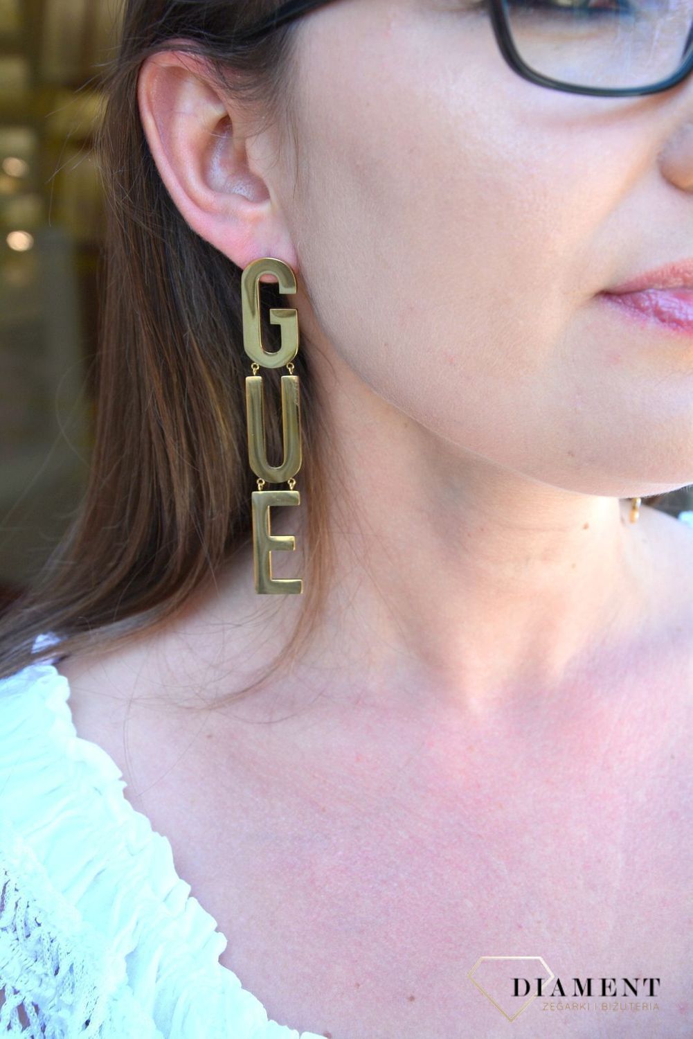 Kolczyki GUESS stalowe pozłacane duży napis Guess UBE20003. Stalowe kolczyki pozłacane duży napis Guess. Wiszące pozłacane kolczyki z wygodnym zapięciem na sztyft. Kolczyki zostały wykonane w modny sposób. Idealnie k.jpg