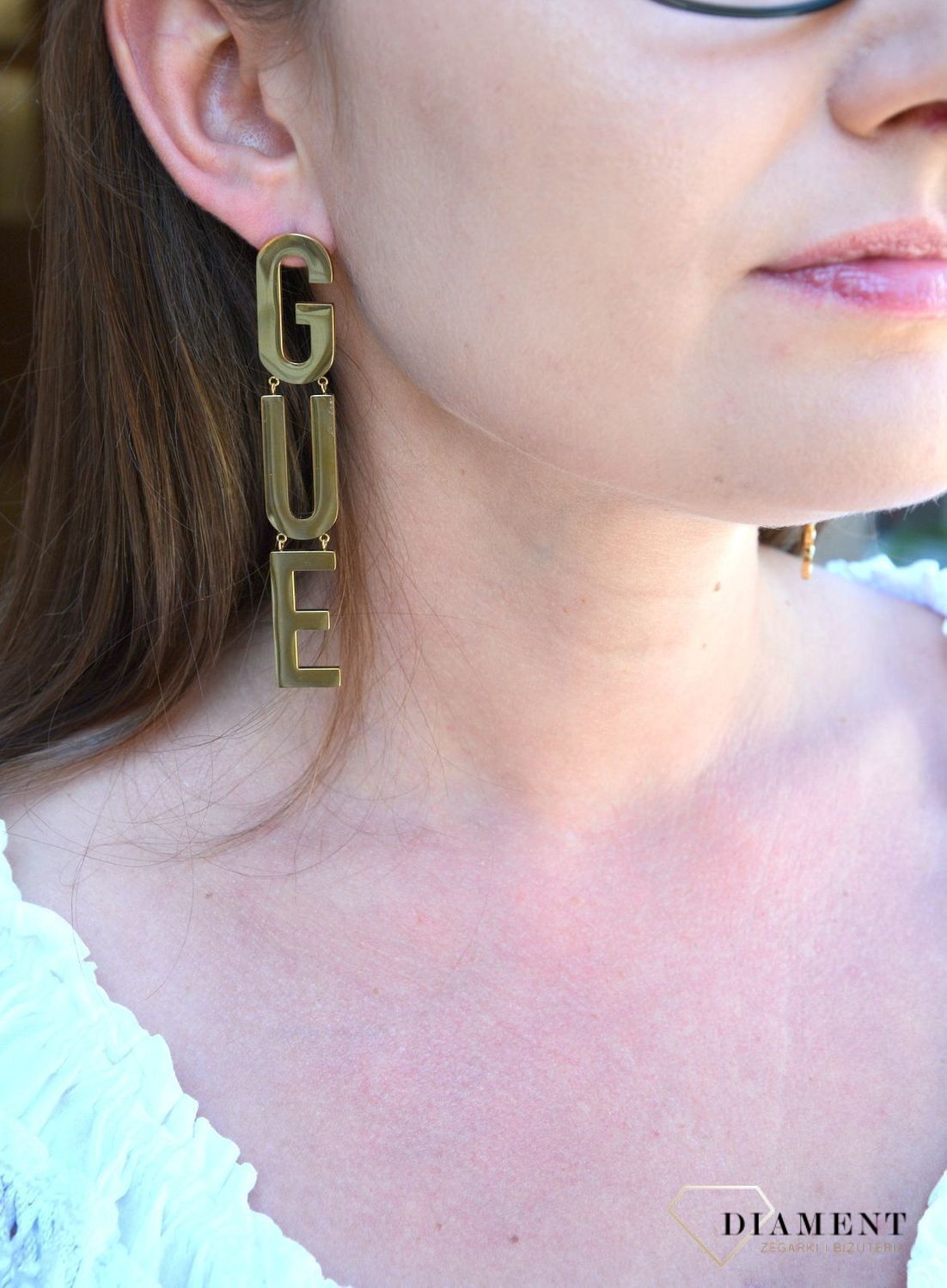 Kolczyki GUESS stalowe pozłacane duży napis Guess UBE20003. Stalowe kolczyki pozłacane duży napis Guess. Wiszące pozłacane kolczyki z wygodnym zapięciem na sztyft. Kolczyki zostały wykonane w modny sposób. Idealnie k.jpg