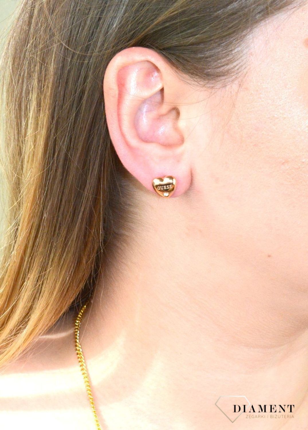 Kolczyki serca GUESS różowe złoto z cyrkonią UBE70106. Stalowe kolczyki w kształcie serca ozdobione napisem Guess i błyszczącą cyrkonią. Kolczyki w kolorze różowego złota, wypukłe..jpg
