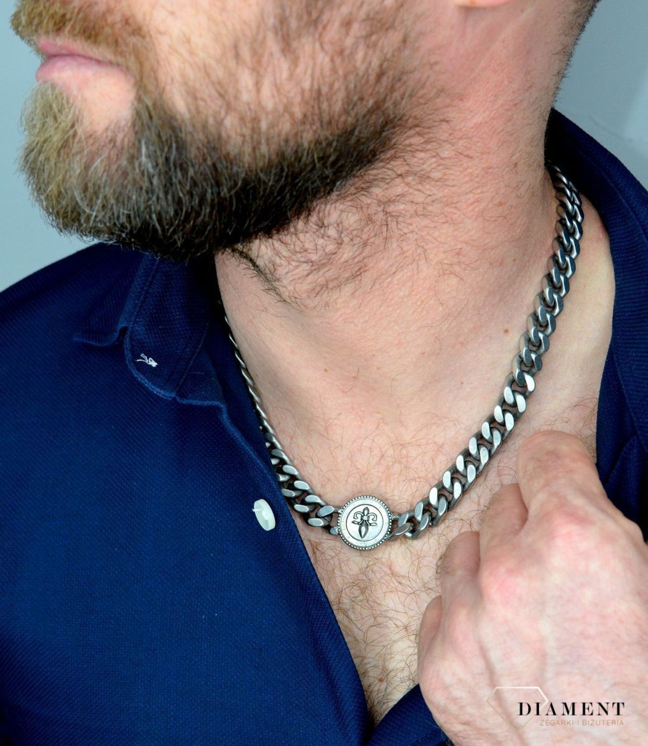 Naszyjnik męski GUESS w kolorze srebra z monetą  UMN70006.  Naszyjnik w formie srebrnej pancerki z logiem GUESS. Zawieszka w kształcie monety z motywem lilii i gra.jpg