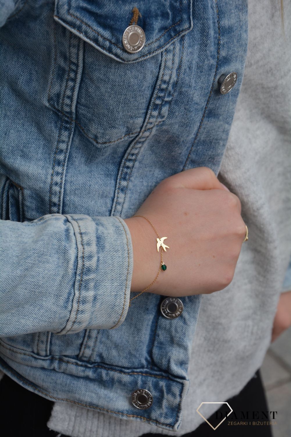 Złota bransoletka wykonana z delikatnego, ażurowego łańcuszka oraz subtelnej zawieszki w formie jaskółki. Całość dopełnia drobne zielone szkiełko..jpg