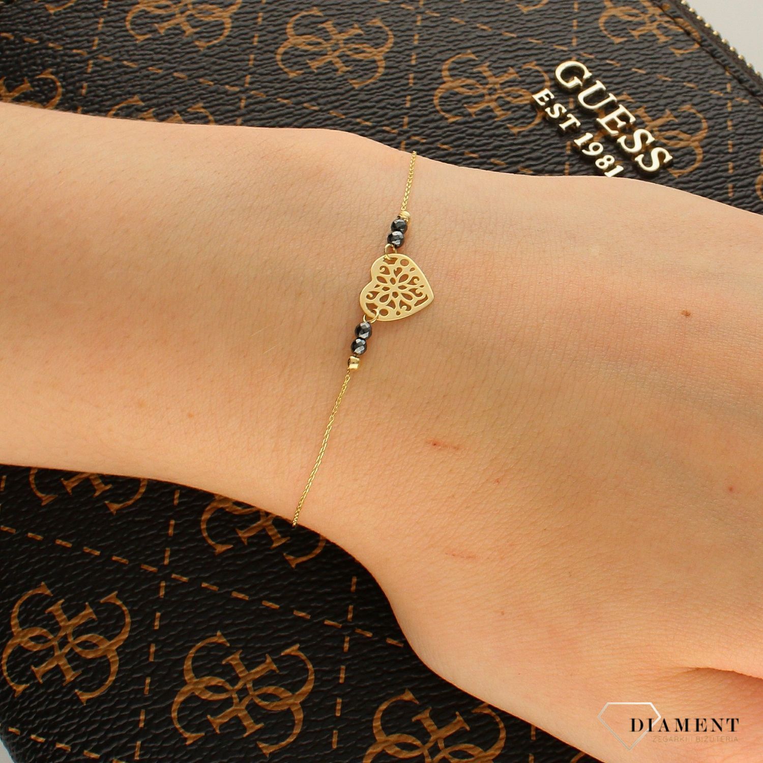 Bransoletka złota próby 333 serce ZW-X-X09-N19-DW17835. Złota bransoletka z elementem ozdobnym w kształcie serca oraz czarnymi kulkami z obu stron, to dodatek, który zachwyca swoją subtelnością i beztroską elegancją. .png