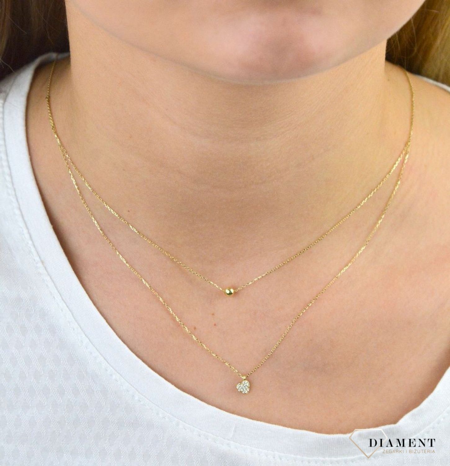 Złoty naszyjnik próby 333 serce z cyrkoniami i kuleczką ZW-X-X09-N45-CB18583. Złoty naszyjnik celebrytka warstwowa z elementami ozdobnym w postaci serca z cyrkoniami i kuleczką. .png