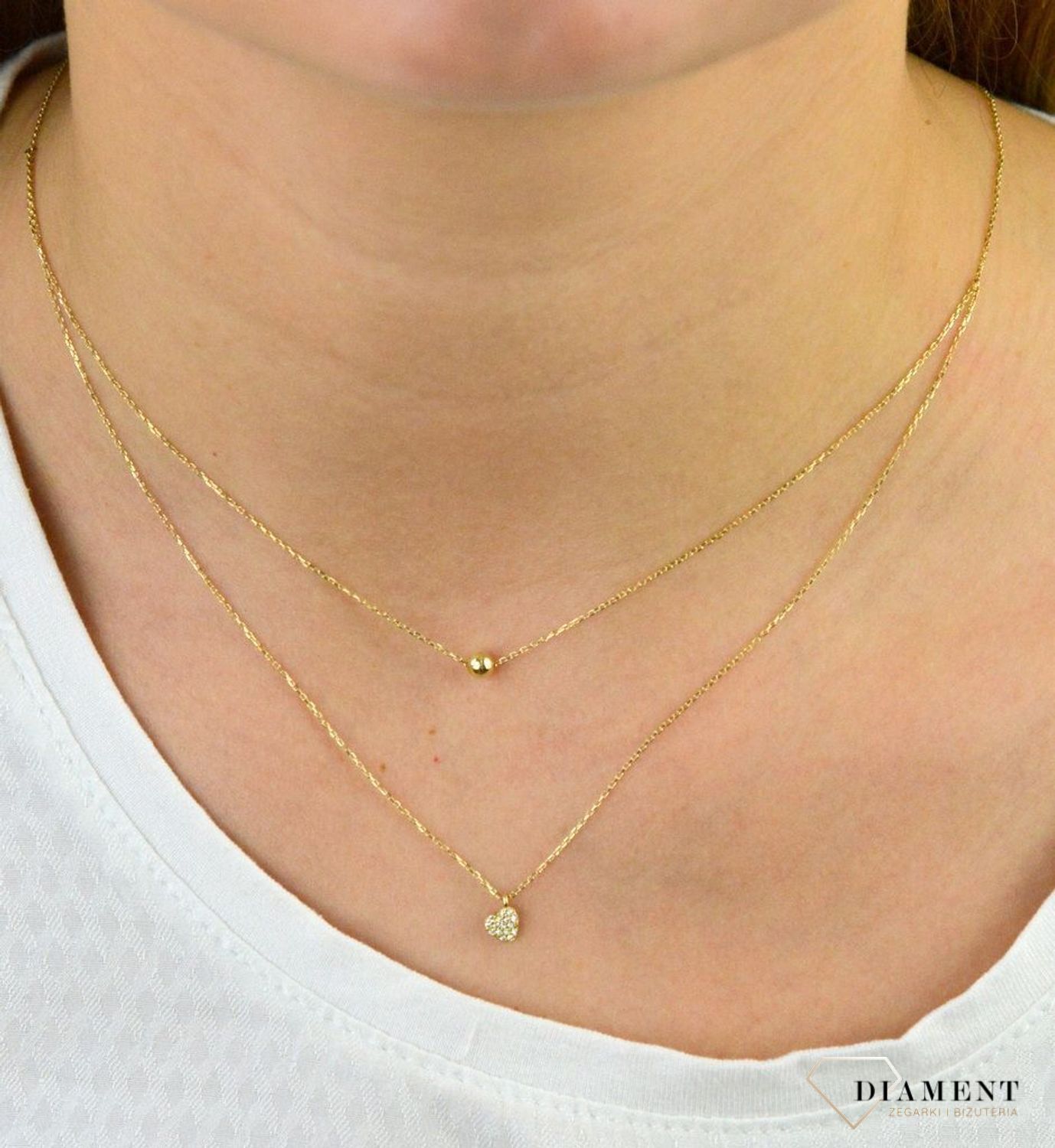 Złoty naszyjnik próby 333 serce z cyrkoniami i kuleczką ZW-X-X09-N45-CB18583. Złoty naszyjnik celebrytka warstwowa z elementami ozdobnym w postaci serca z cyrkoniami i kuleczką. .png